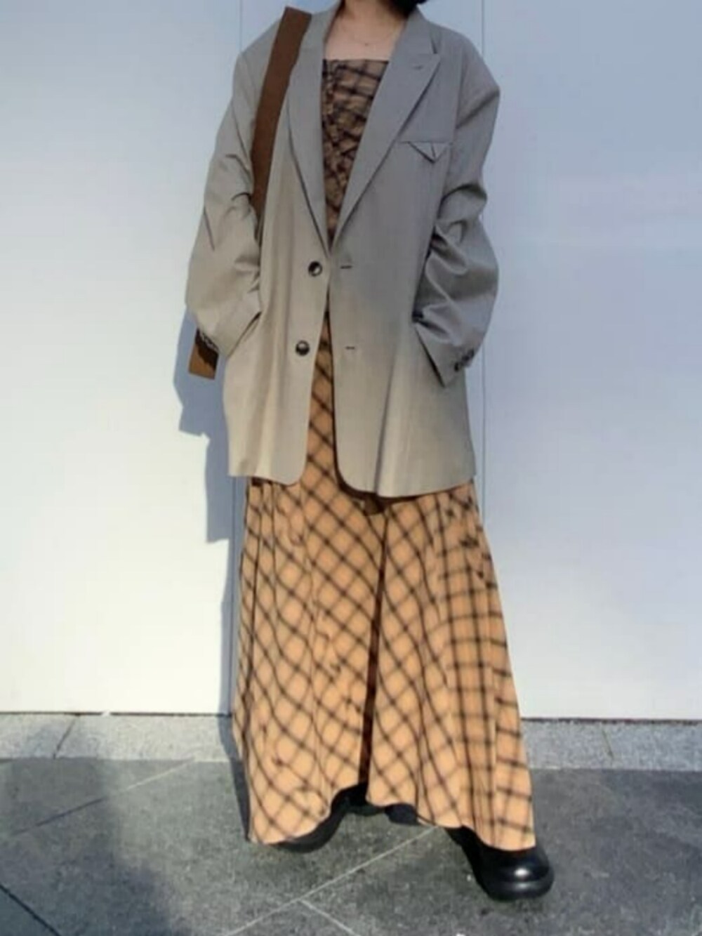 イエロー系のボストンバッグ、ベージュ系のテーラードジャケット、ベージュ系のワンピースを着用したレディースの冬コーディネートの2枚目の写真