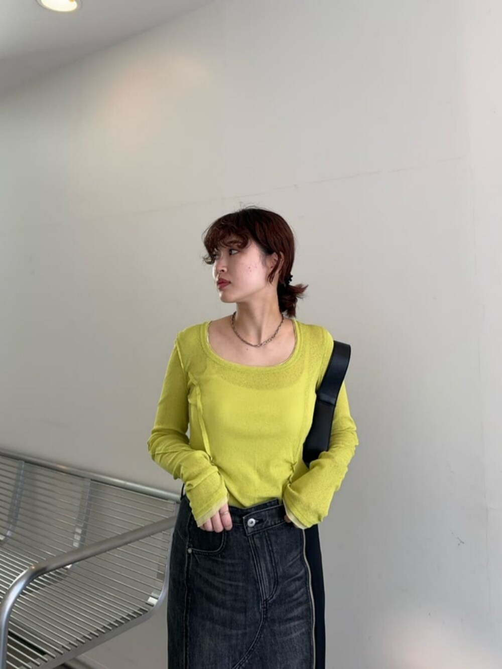 ブラック系のショルダーバッグ、グリーン系のTシャツ/カットソー、ブラック系のデニムスカートを着用したレディースの冬コーディネートの2枚目の写真