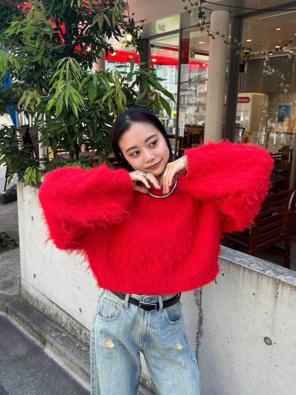 レッド系のニット/セーター、ブルー系のデニムパンツを着用したレディースの夏コーディネートの2枚目の写真