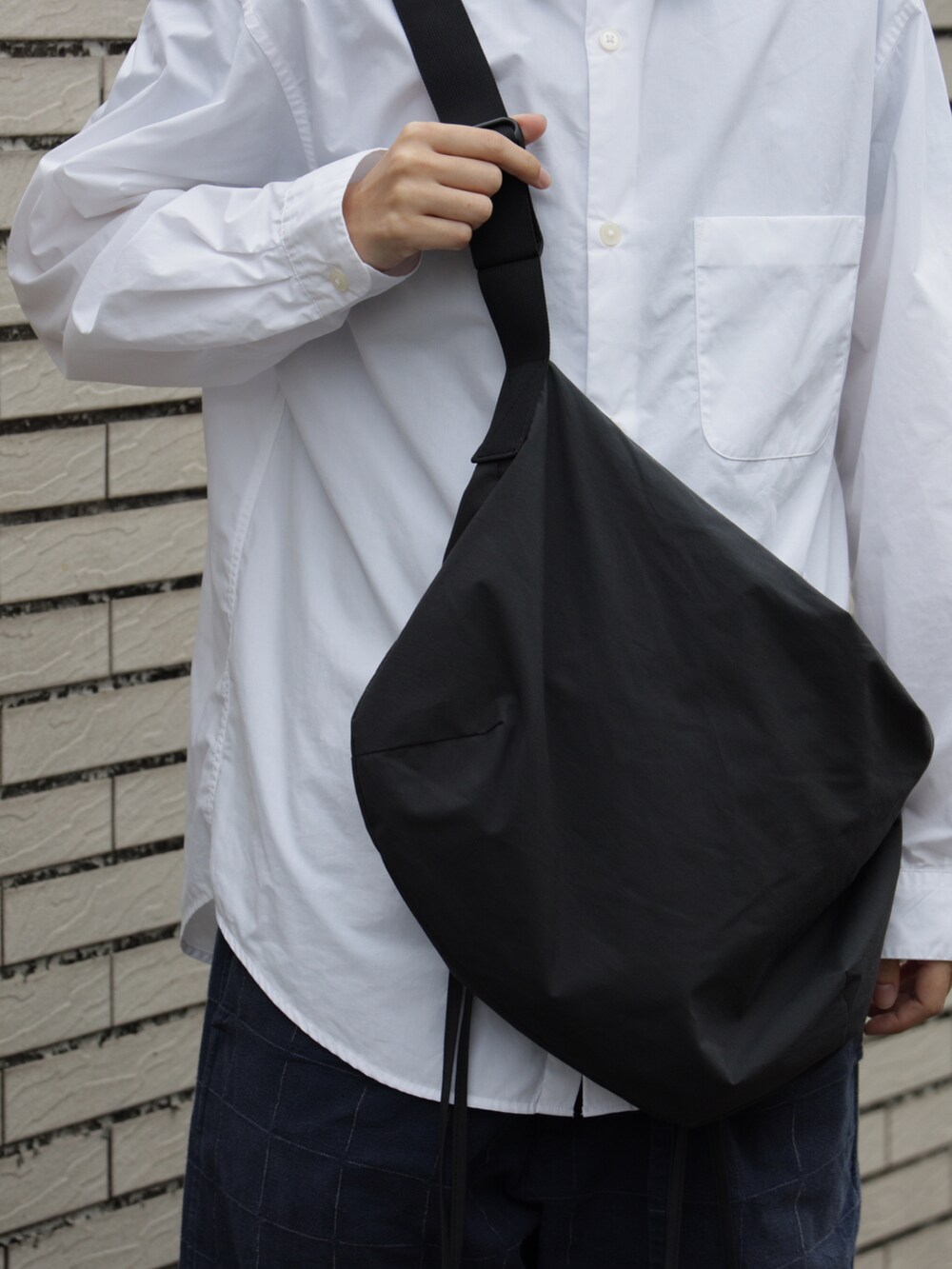 ブルー系のチノパンツ、ブラック系のバッグ、ホワイト系のシャツ/ブラウスを着用したメンズの冬コーディネートの3枚目の写真