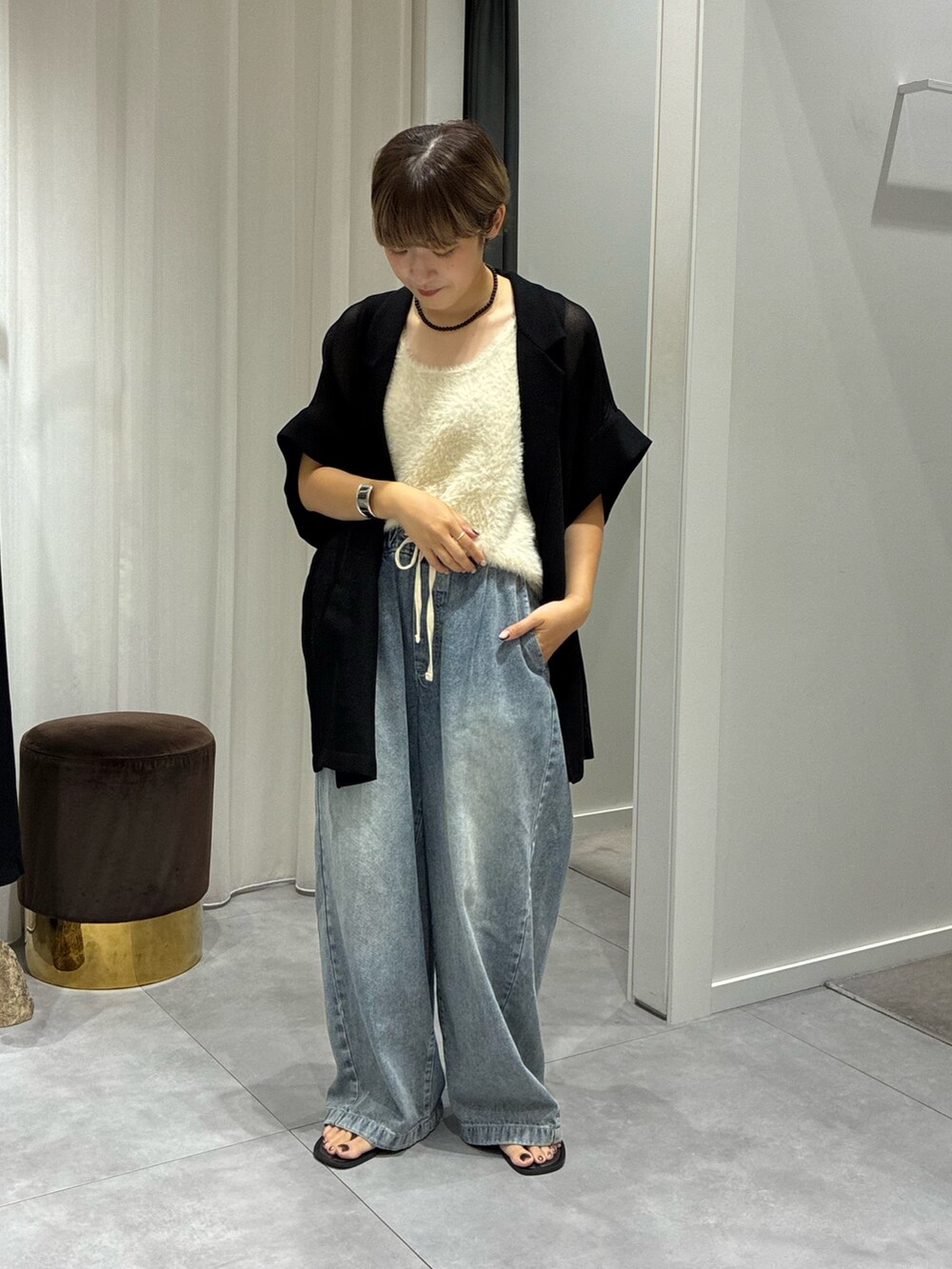 ブルー系のデニムパンツ、ホワイト系のニット/セーター、ブラック系のテーラードジャケットを着用したレディースの夏コーディネートの2枚目の写真