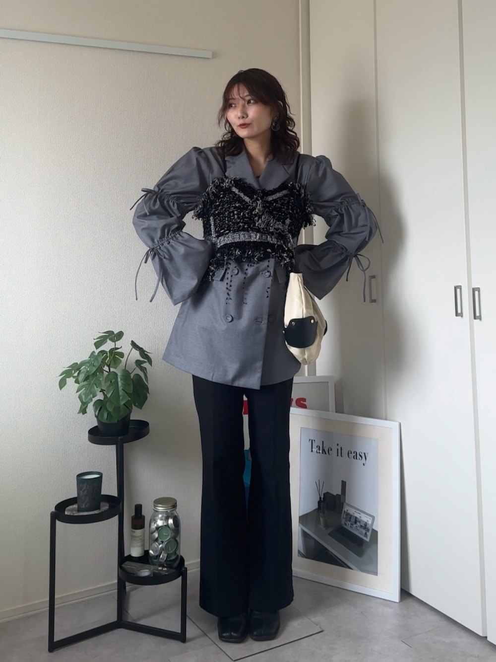 ブラック系のブーツ、ホワイト系のバッグ、ブラック系のベストを着用したレディースの冬コーディネートの2枚目の写真