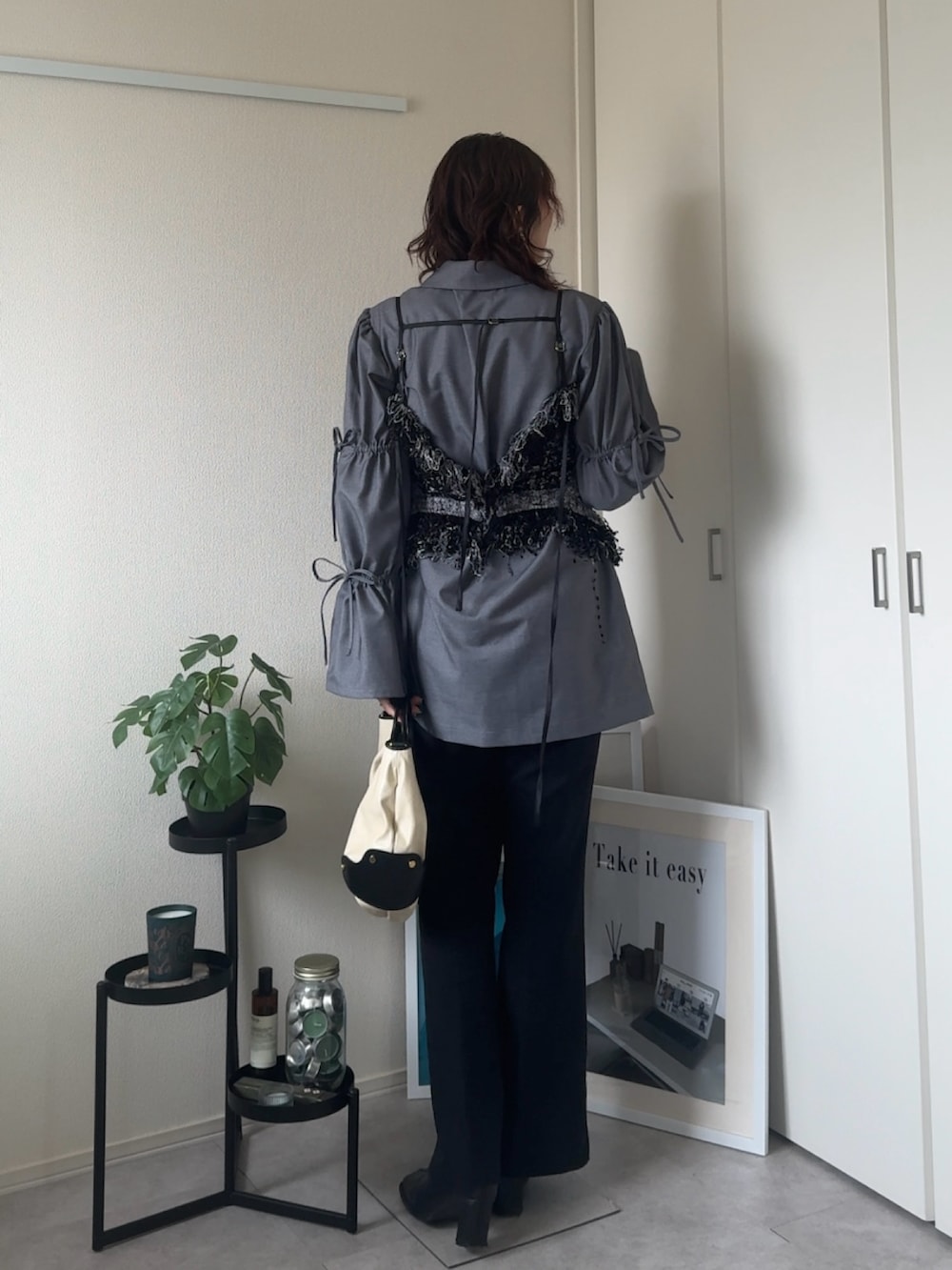 ブラック系のブーツ、ホワイト系のバッグ、ブラック系のベストを着用したレディースの冬コーディネートの3枚目の写真