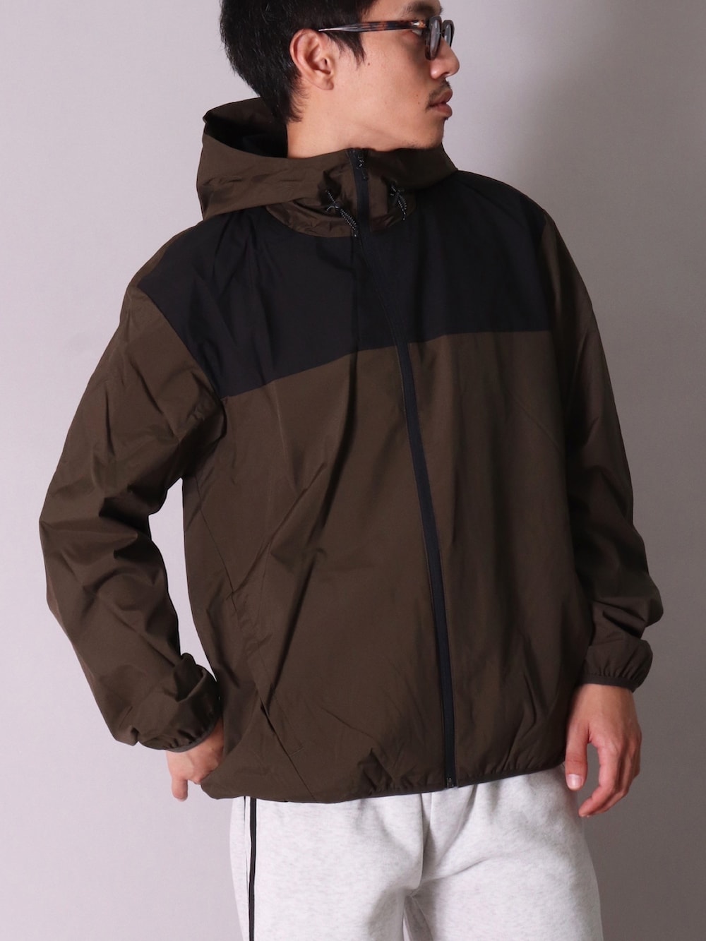 グリーン系のナイロンジャケット、ブラック系のスニーカー、グレー系のスウェットパンツを着用したメンズの春コーディネートの2枚目の写真