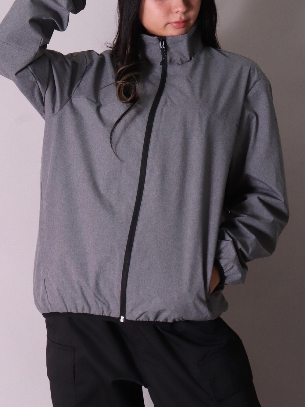 グレー系のナイロンジャケット、ブラック系のカーゴパンツ、ブラック系のナイロンジャケットを着用したレディースの冬コーディネートの3枚目の写真