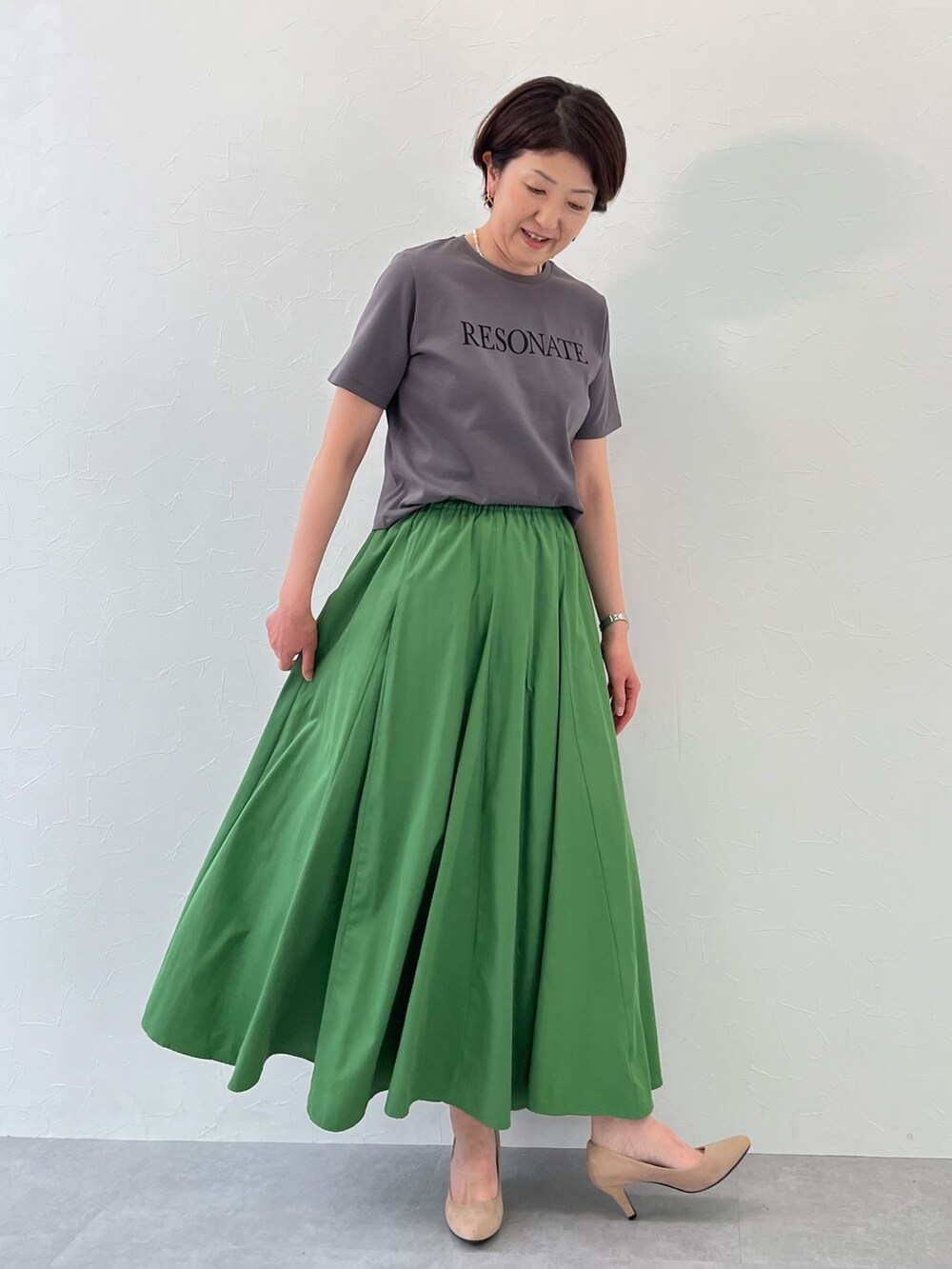 グリーン系のスカート、ホワイト系のテーラードジャケット、グレー系のTシャツ/カットソーを着用したレディースの春コーディネートの2枚目の写真