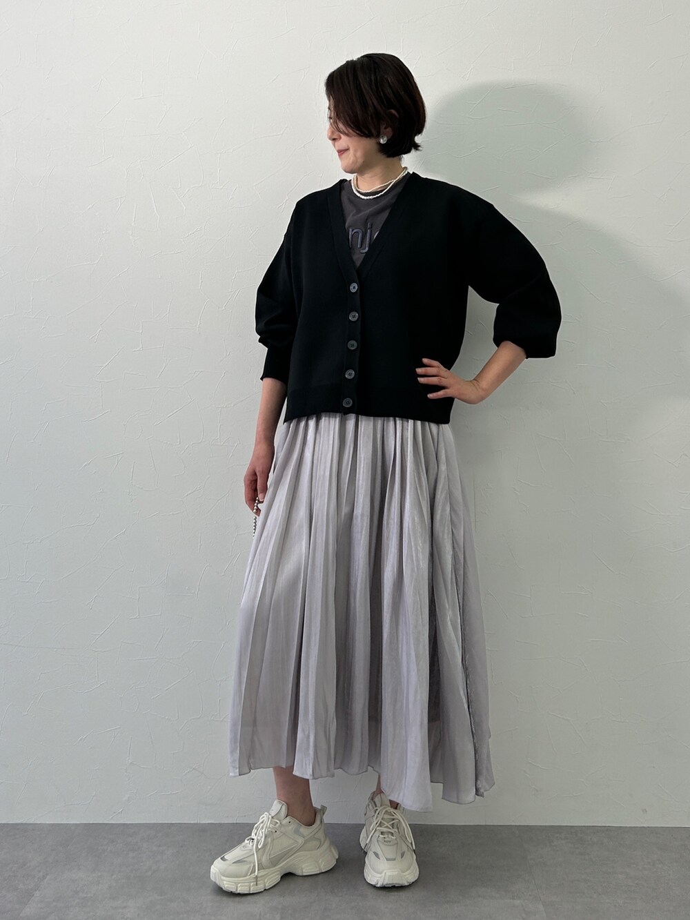 グレー系のスカート、ブラック系のカーディガン/ボレロ、グレー系のTシャツ/カットソーを着用したレディースの冬コーディネートの2枚目の写真