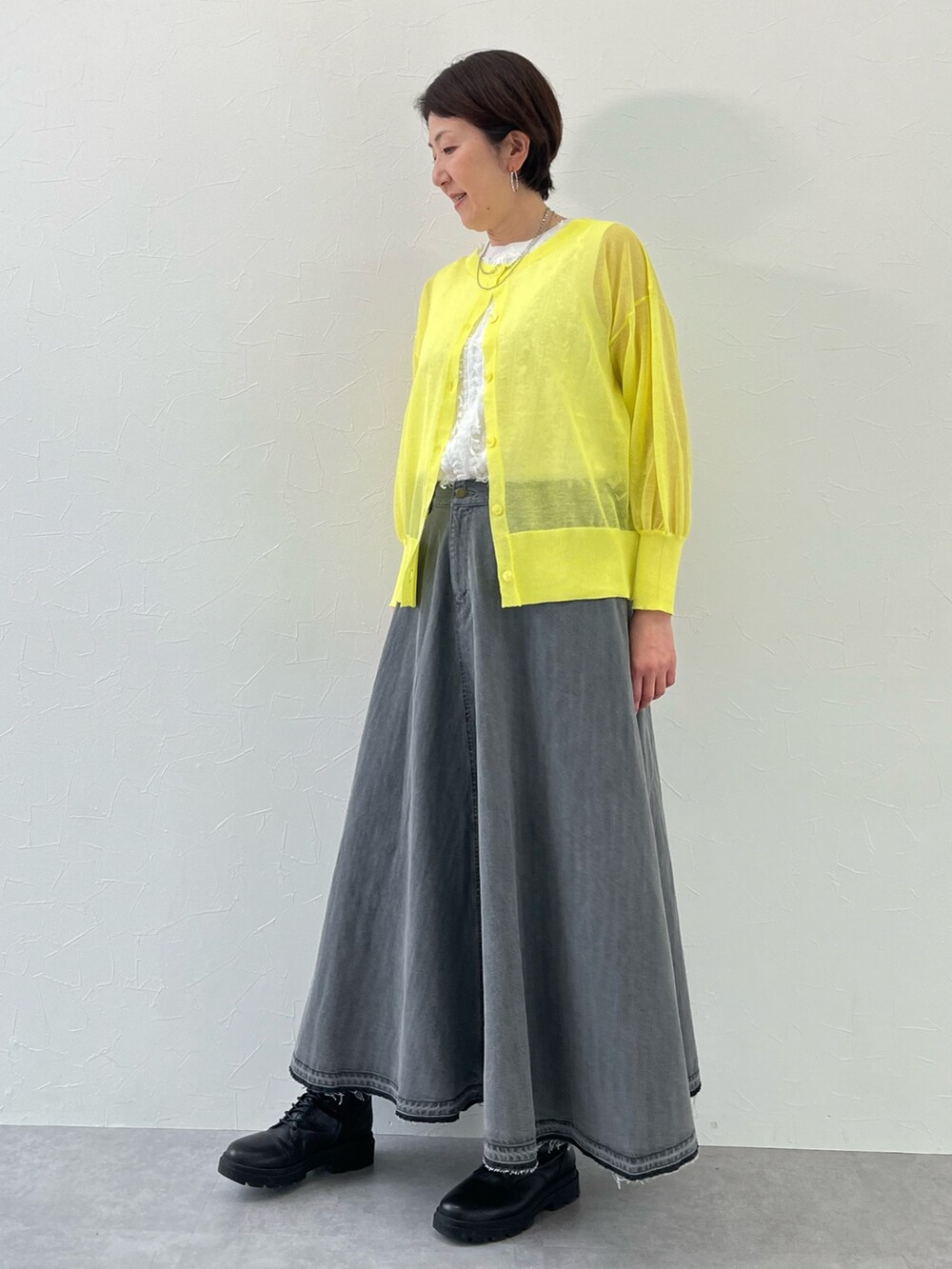 イエロー系のニット/セーター、ホワイト系のニット/セーター、グレー系のスカートを着用したレディースの春コーディネートの2枚目の写真