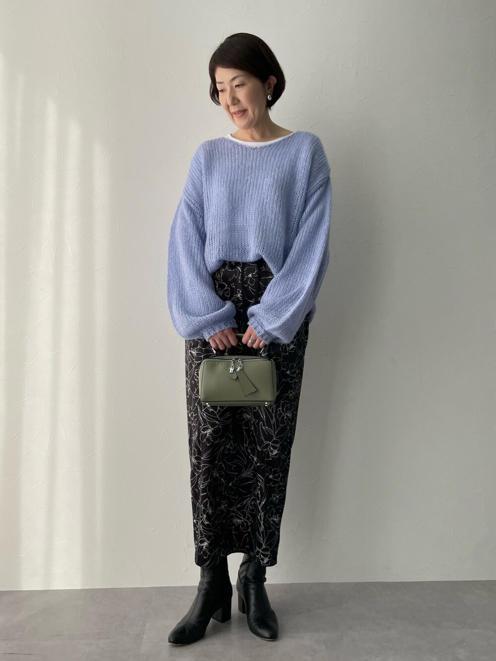 ブルー系のニット/セーター、ブラック系のスカートを着用したレディースの冬コーディネートの2枚目の写真