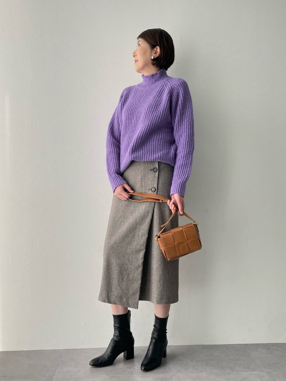 パープル系のニット/セーター、ブラウン系のスカートを着用したレディースの冬コーディネートの2枚目の写真