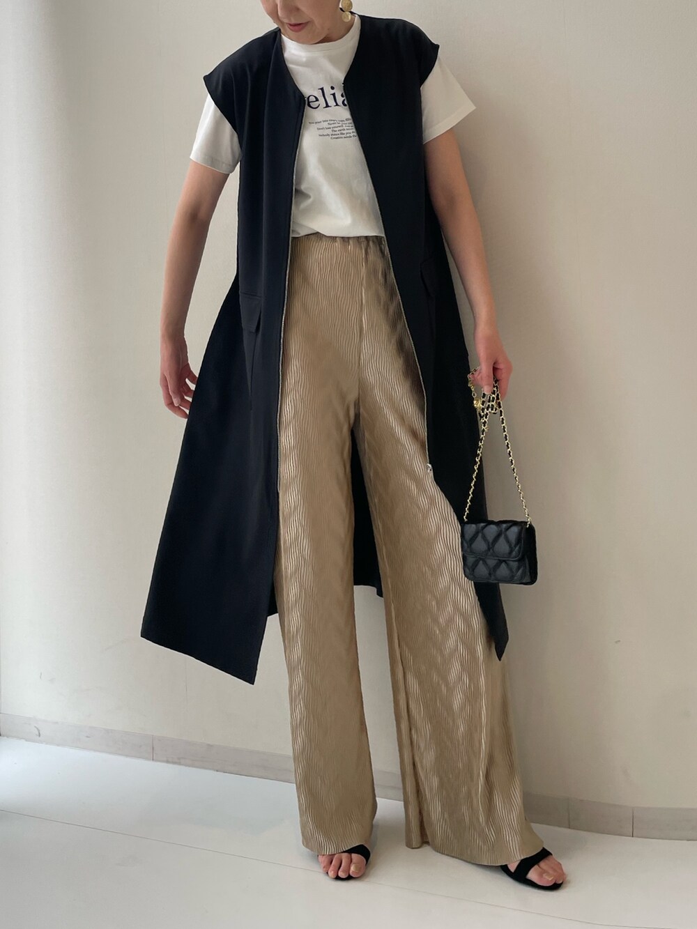 ホワイト系のTシャツ/カットソー、ブラック系のワンピース、ブラウン系のパンツを着用したレディースの春コーディネートの2枚目の写真