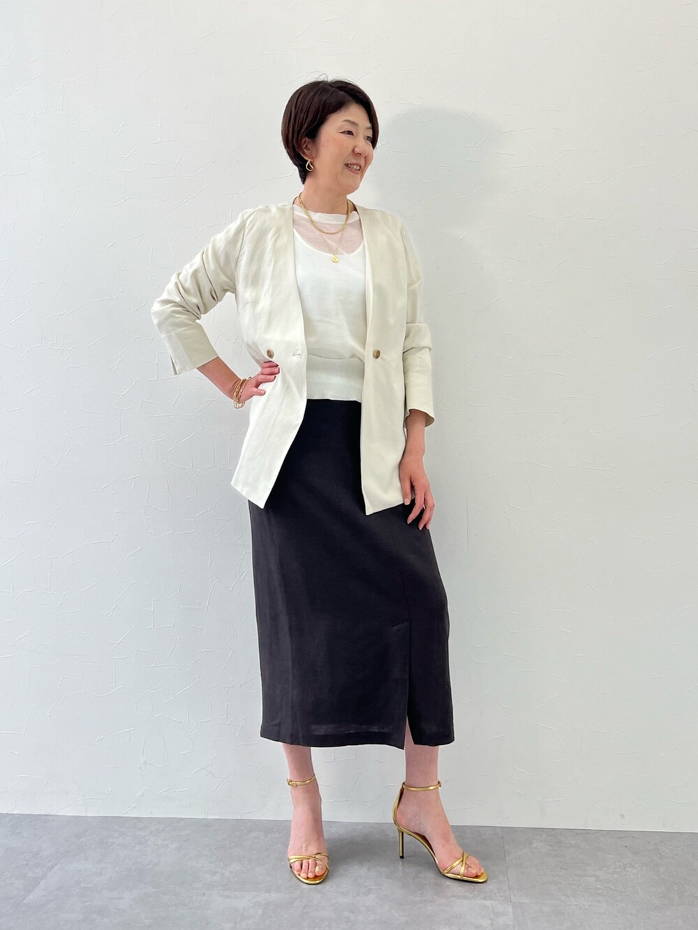 ホワイト系のノーカラージャケット、グレー系のスカート、ホワイト系のニット/セーターを着用したレディースの春コーディネートの2枚目の写真