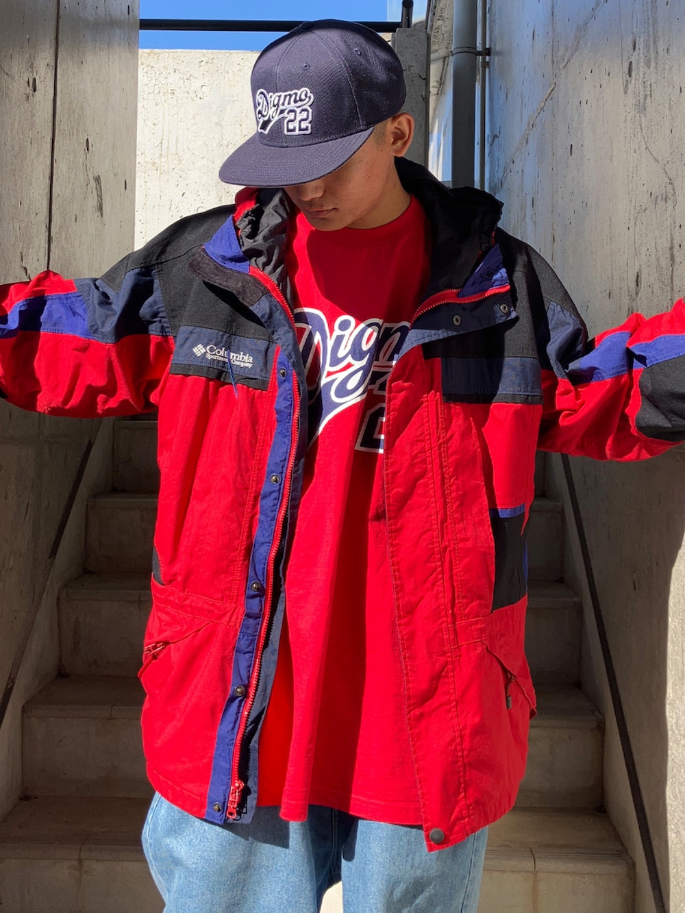 レッド系のTシャツ/カットソー、レッド系のマウンテンパーカー、ブルー系のデニムパンツを着用したメンズの秋コーディネートの2枚目の写真