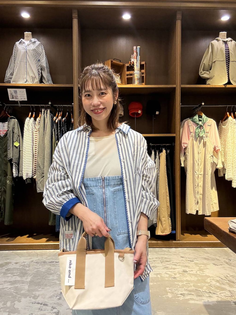 ブルー系のジャンパースカート、ベージュ系のTシャツ/カットソー、その他のショルダーバッグを着用したレディースの春コーディネートの6枚目の写真