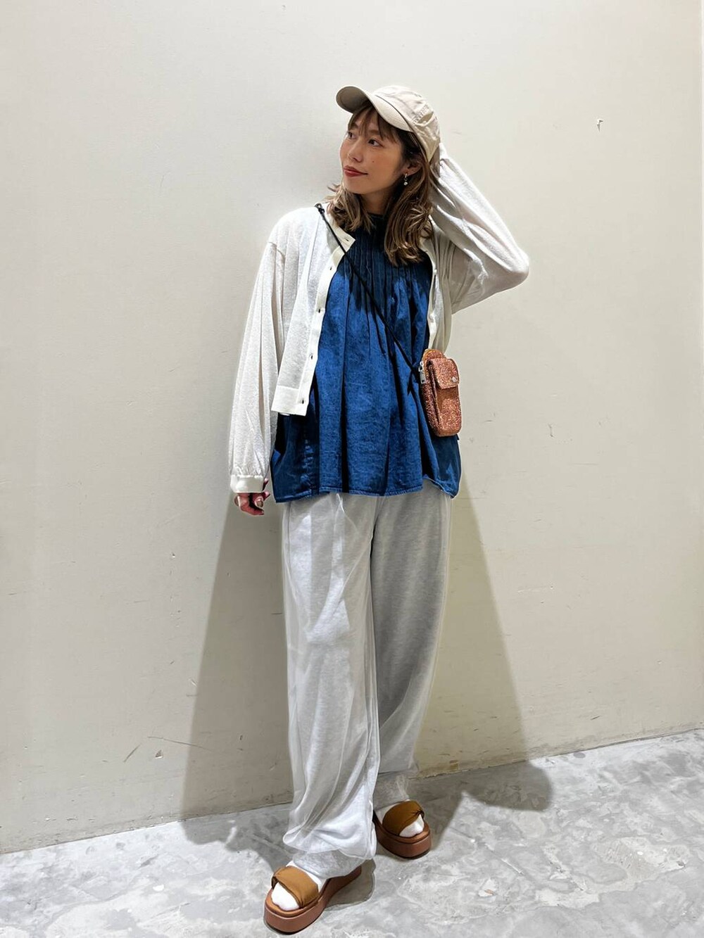 イエロー系のサンダル、ブルー系のベスト、オレンジ系のショルダーバッグを着用したレディースの春コーディネートの3枚目の写真