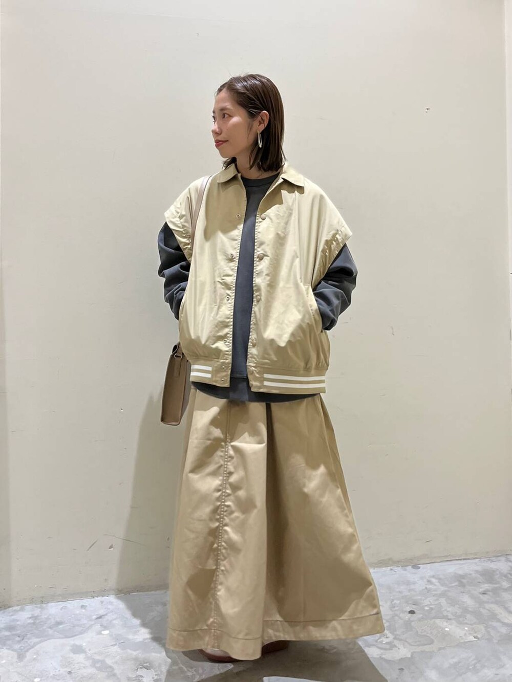 ベージュ系のスニーカー、ベージュ系のスタジャン、ベージュ系のスカートを着用したレディースの冬コーディネートの3枚目の写真