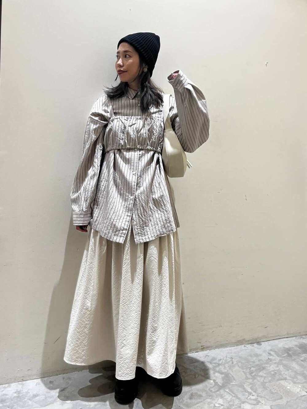 ベージュ系のショルダーバッグ、ブラック系のブーツ、ベージュ系のシャツ/ブラウスを着用したレディースの春コーディネートの5枚目の写真