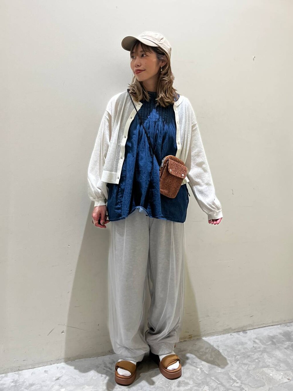 イエロー系のサンダル、ブルー系のベスト、オレンジ系のショルダーバッグを着用したレディースの春コーディネートの2枚目の写真