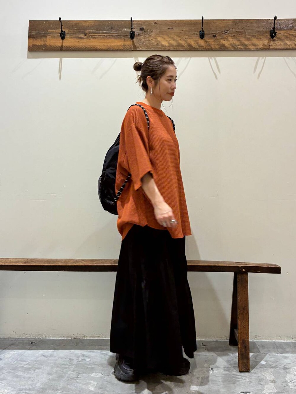 ブラック系のスカート、オレンジ系のTシャツ/カットソー、ブラック系のバックパック/リュックを着用したレディースの夏コーディネートの5枚目の写真