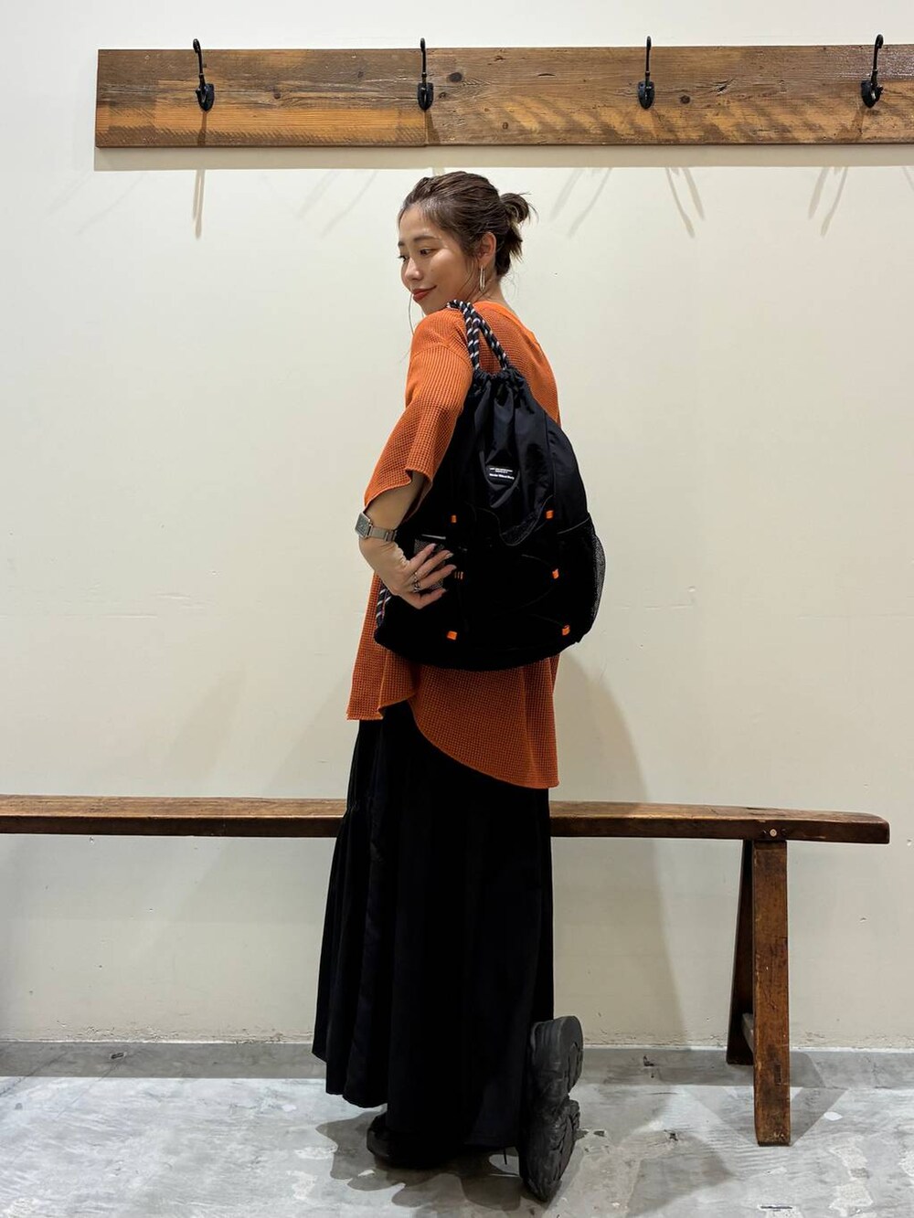 ブラック系のスカート、オレンジ系のTシャツ/カットソー、ブラック系のバックパック/リュックを着用したレディースの夏コーディネートの9枚目の写真