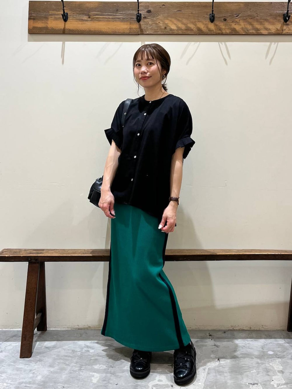 グリーン系のスカート、ブラック系のショルダーバッグ、ブラック系のバレエシューズを着用したレディースの春コーディネートの7枚目の写真