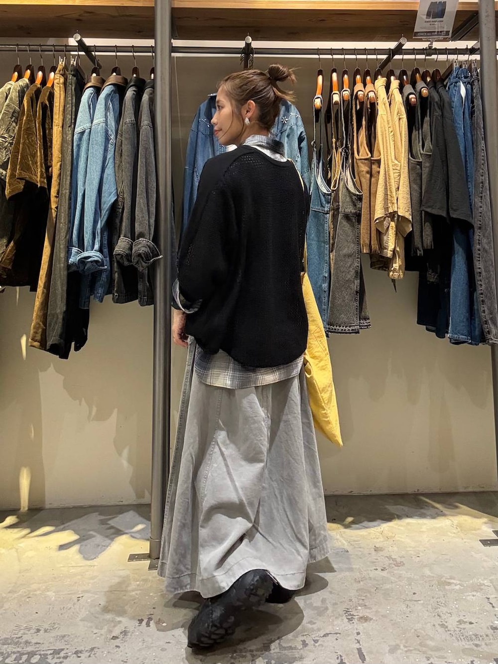 イエロー系のトートバッグ、グレー系のスカート、ブラック系のスニーカーを着用したレディースの秋コーディネートの2枚目の写真