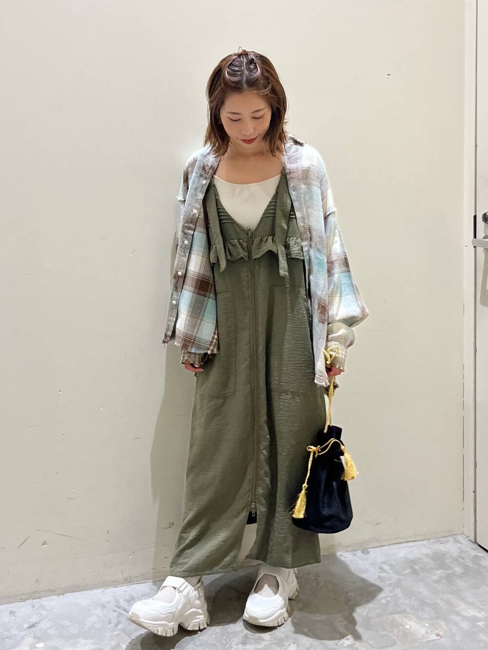 グリーン系のシャツ/ブラウス、グリーン系のジャンパースカート、ベージュ系のスニーカーを着用したレディースの秋コーディネートの4枚目の写真