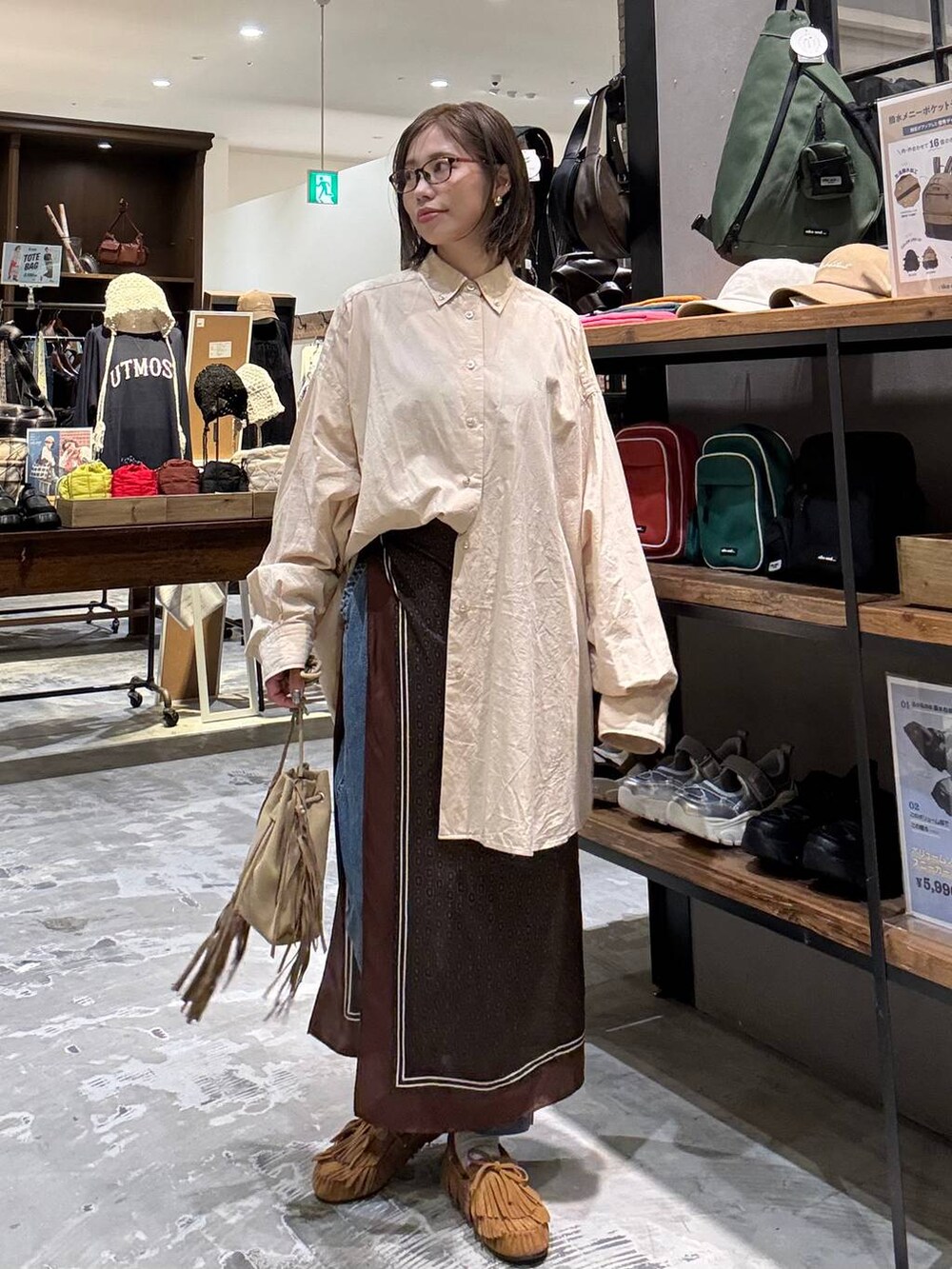 ベージュ系のシャツ/ブラウス、イエロー系のモカシン/デッキシューズ、ベージュ系のショルダーバッグを着用したレディースの秋コーディネートの2枚目の写真