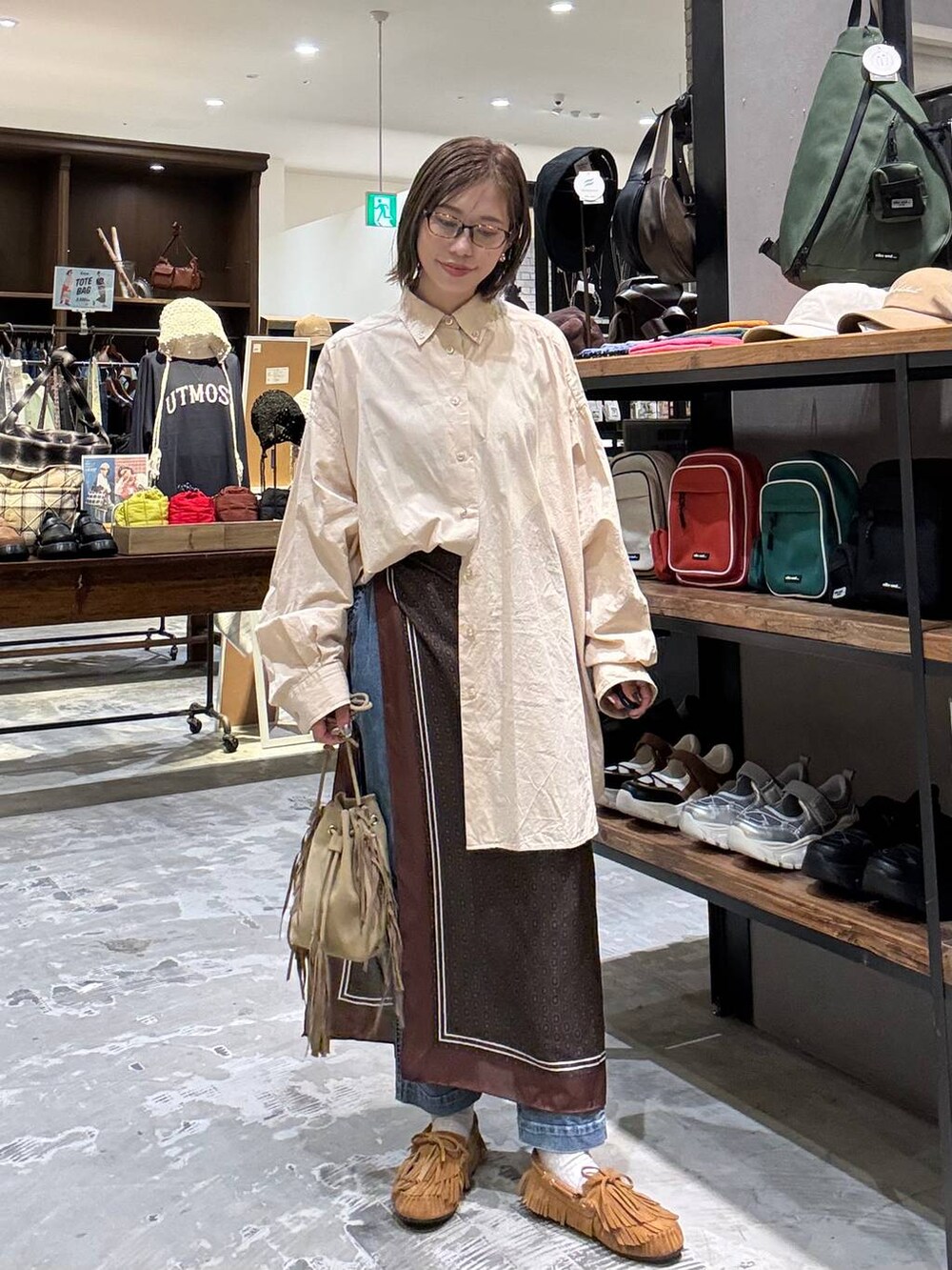 ベージュ系のシャツ/ブラウス、イエロー系のモカシン/デッキシューズ、ベージュ系のショルダーバッグを着用したレディースの秋コーディネートの4枚目の写真