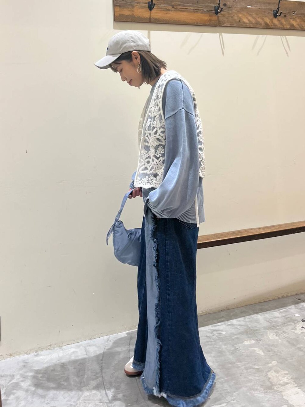 ベージュ系のスニーカー、ブルー系のデニムスカート、ブルー系のショルダーバッグを着用したレディースの冬コーディネートの3枚目の写真