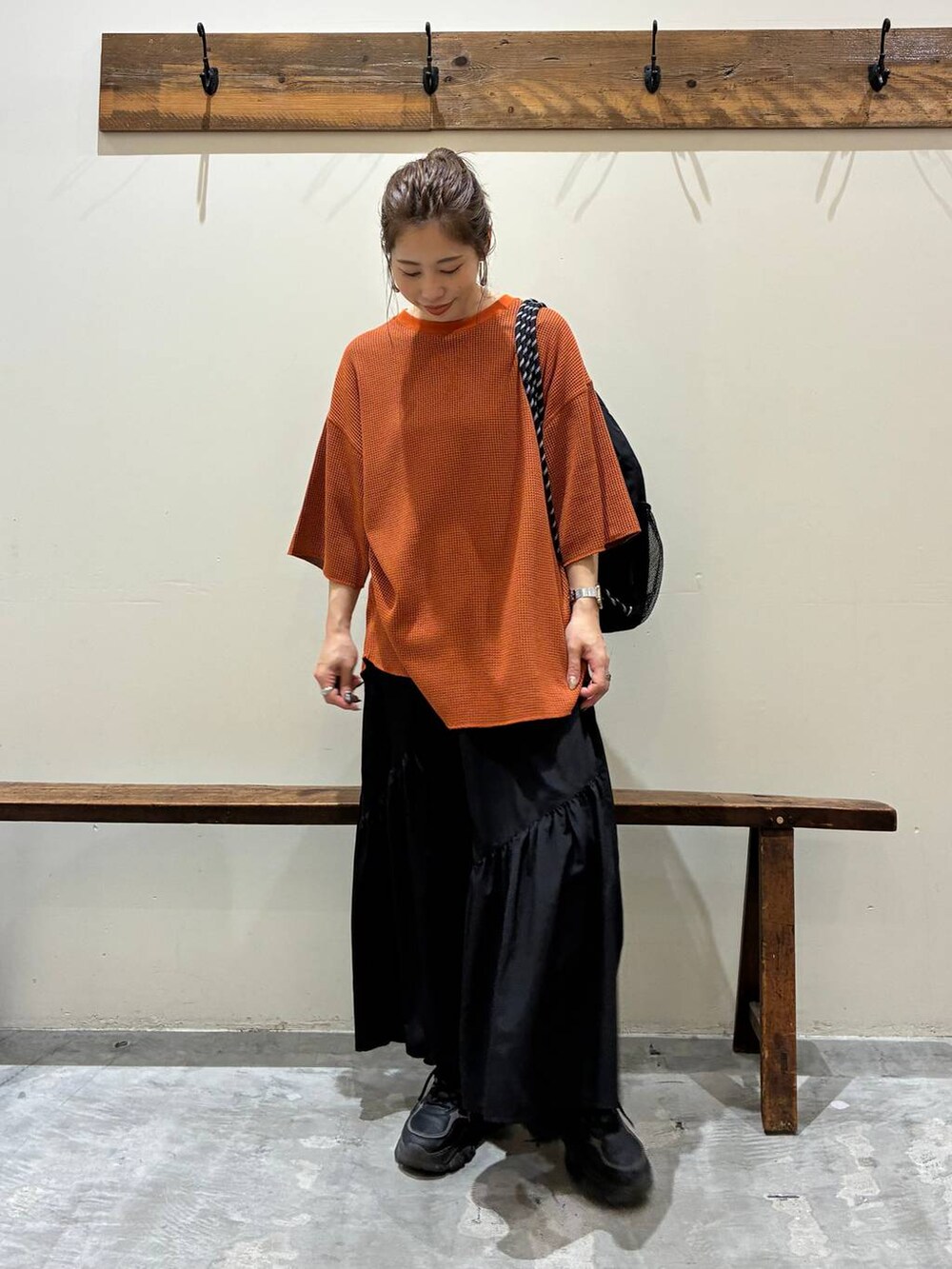 ブラック系のスカート、オレンジ系のTシャツ/カットソー、ブラック系のバックパック/リュックを着用したレディースの夏コーディネートの6枚目の写真