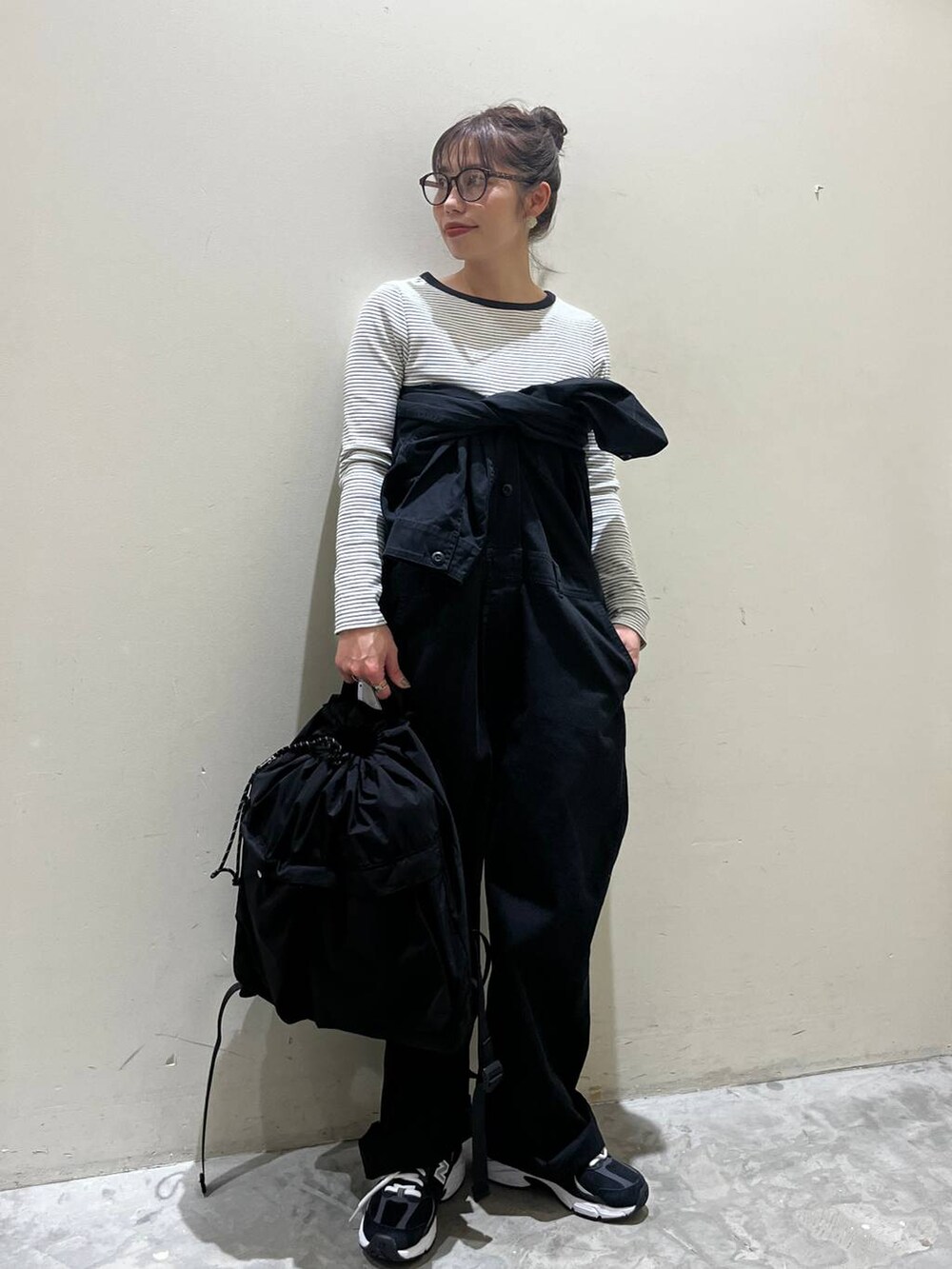 ブラック系のバックパック/リュック、ベージュ系のTシャツ/カットソー、ブラック系のつなぎ/オールインワンを着用したレディースの春コーディネートの4枚目の写真