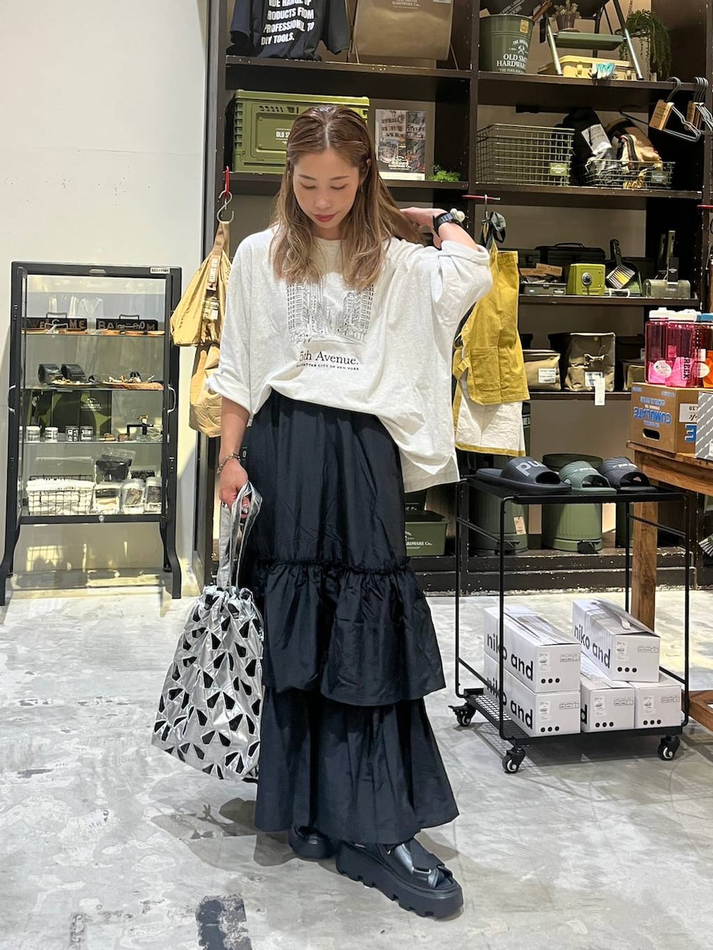 ベージュ系のTシャツ/カットソー、その他のトートバッグ、ブラック系のスカートを着用したレディースの夏コーディネートの2枚目の写真