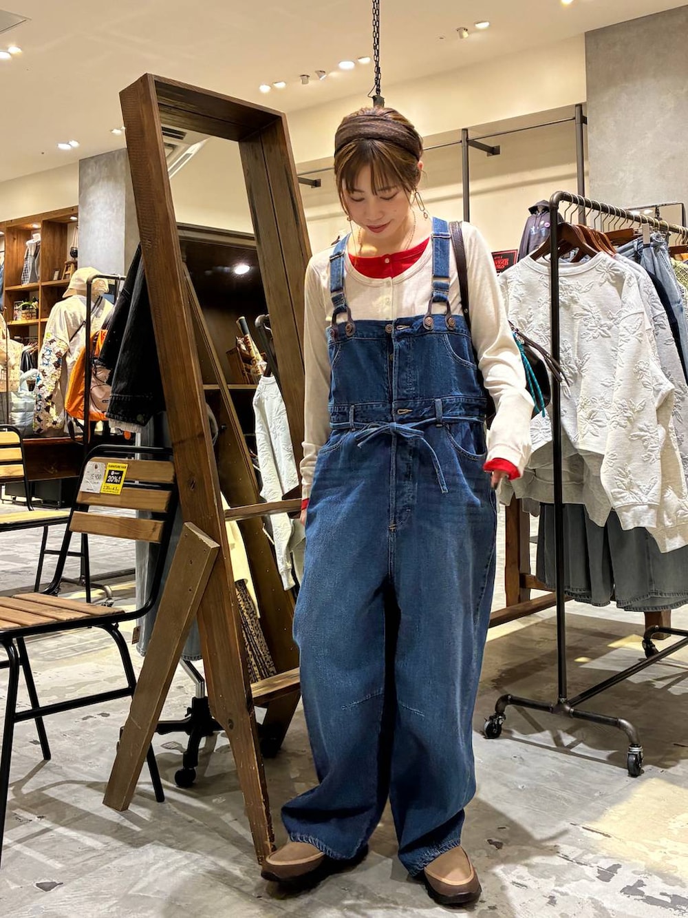 ブラウン系のボストンバッグ、ベージュ系のTシャツ/カットソー、ブルー系のサロペット/オーバーオールを着用したレディースの冬コーディネートの2枚目の写真