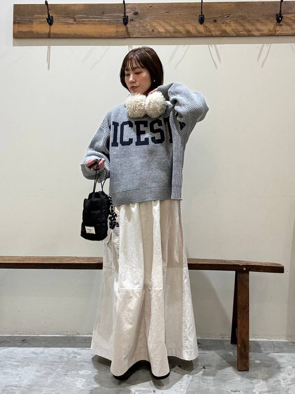 ベージュ系のスカート、ブラック系のショルダーバッグ、グレー系のパンプスを着用したレディースの冬コーディネートの2枚目の写真