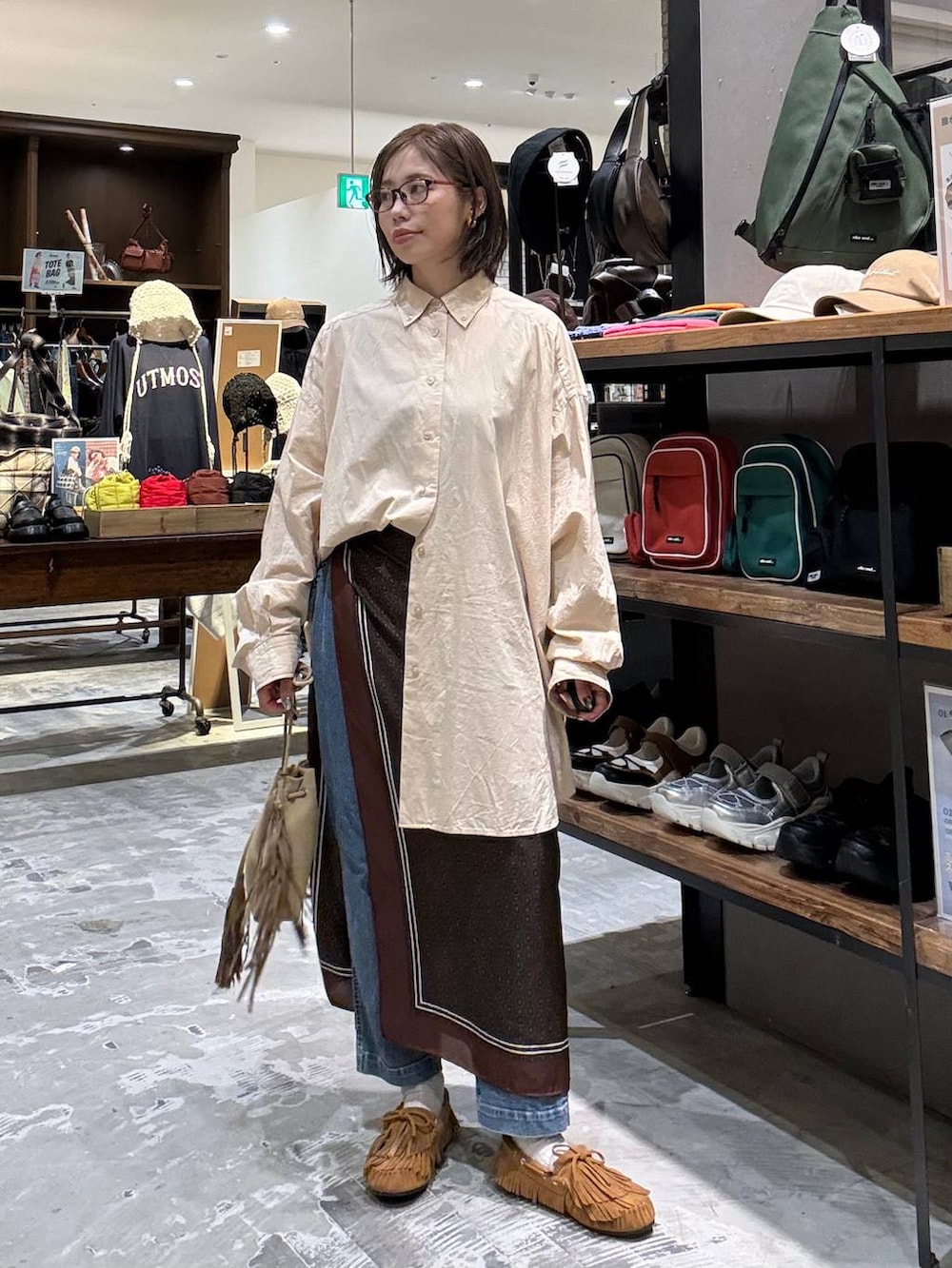 ベージュ系のシャツ/ブラウス、イエロー系のモカシン/デッキシューズ、ベージュ系のショルダーバッグを着用したレディースの秋コーディネートの5枚目の写真