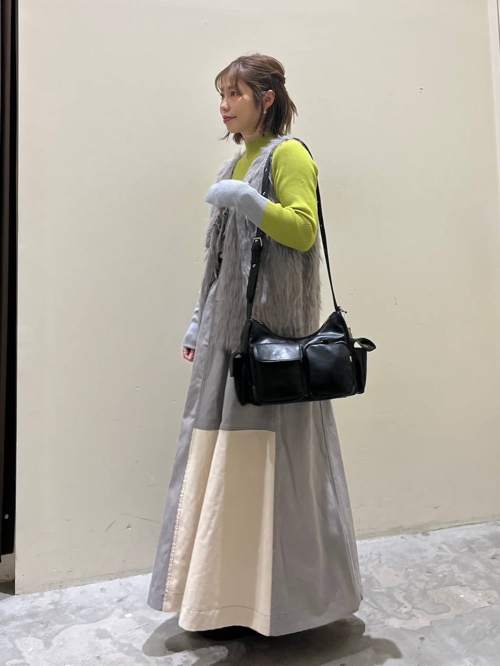 グリーン系のニット/セーター、ブラック系のブーツ、ブラック系のショルダーバッグを着用したレディースの冬コーディネートの2枚目の写真