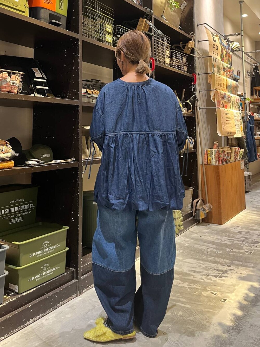 ベージュ系のトートバッグ、ブルー系のデニムパンツ、イエロー系のバレエシューズを着用したレディースの秋コーディネートの3枚目の写真