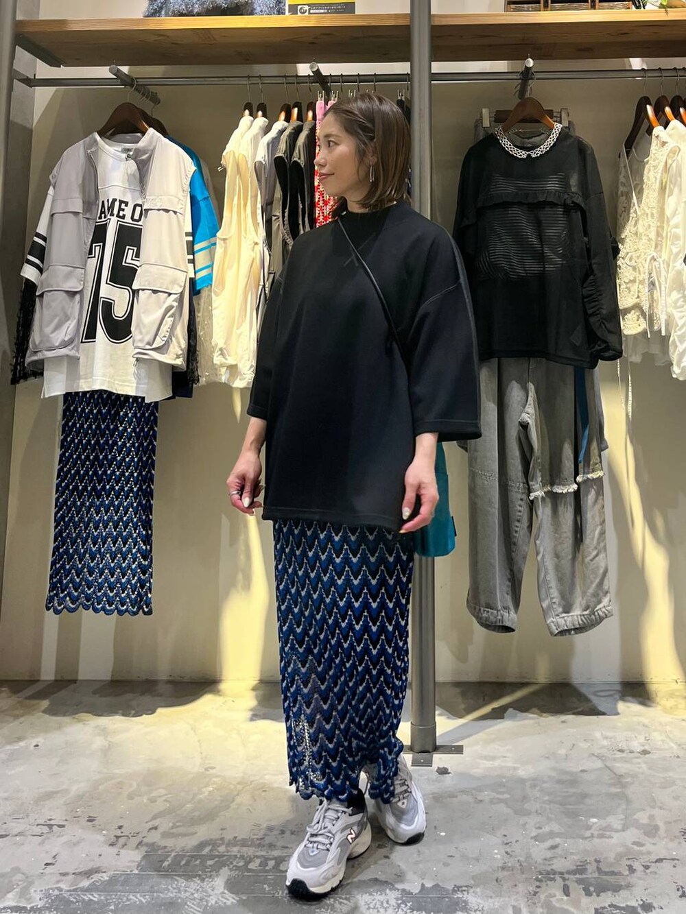 ブルー系のスカート、グレー系のスニーカー、ブルー系のショルダーバッグを着用したレディースの春コーディネートの5枚目の写真