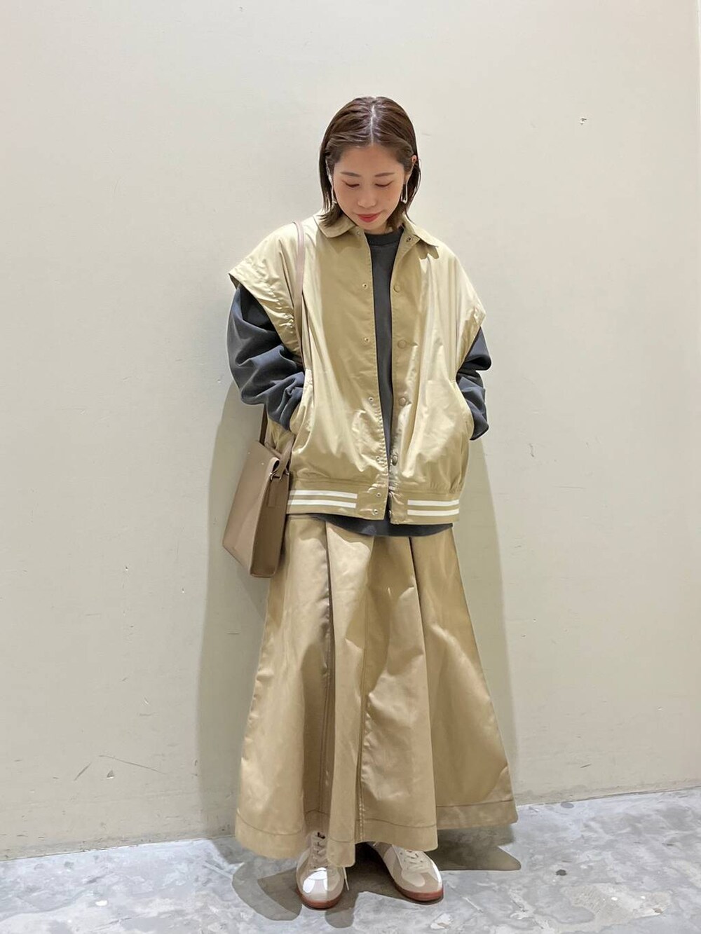 ベージュ系のスニーカー、ベージュ系のスタジャン、ベージュ系のスカートを着用したレディースの冬コーディネートの7枚目の写真