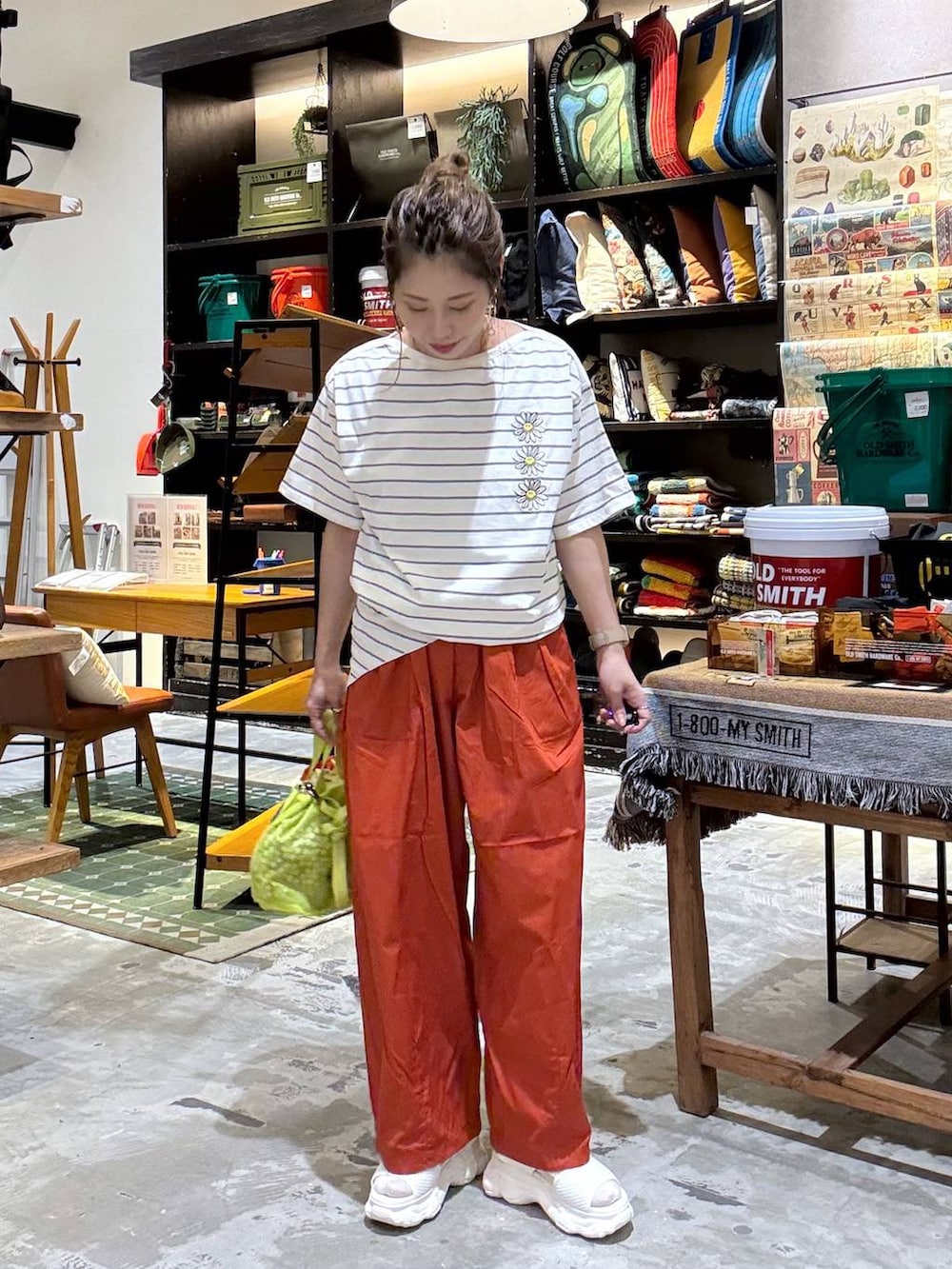 オレンジ系のその他パンツ、オレンジ系のTシャツ/カットソー、イエロー系のショルダーバッグを着用したレディースの春コーディネートの6枚目の写真