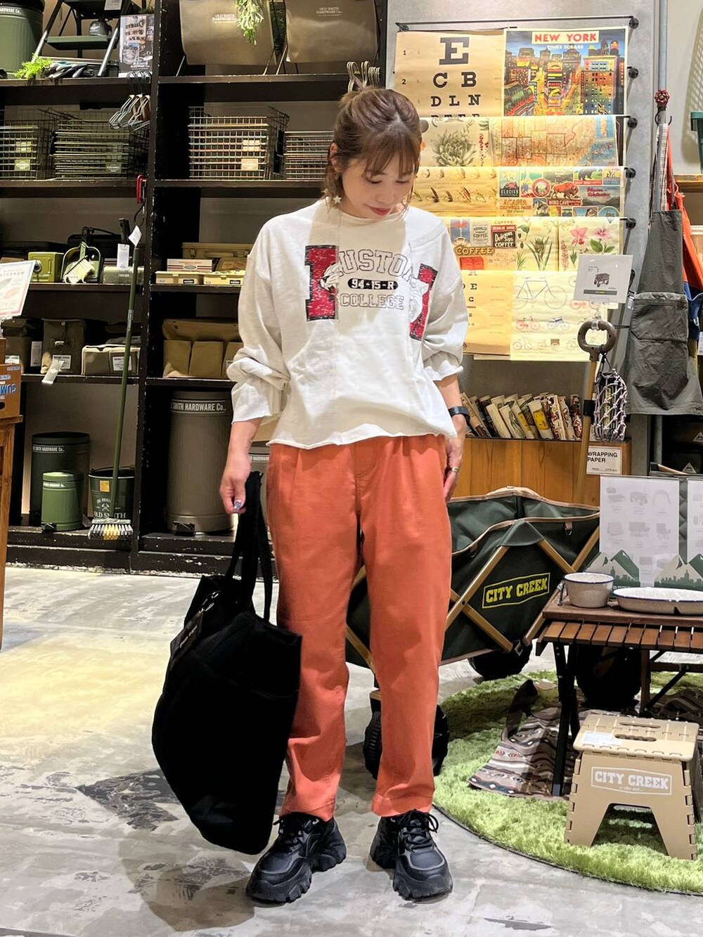 ブラック系のトートバッグ、オレンジ系のその他パンツ、ホワイト系のTシャツ/カットソーを着用したレディースの秋コーディネートの6枚目の写真