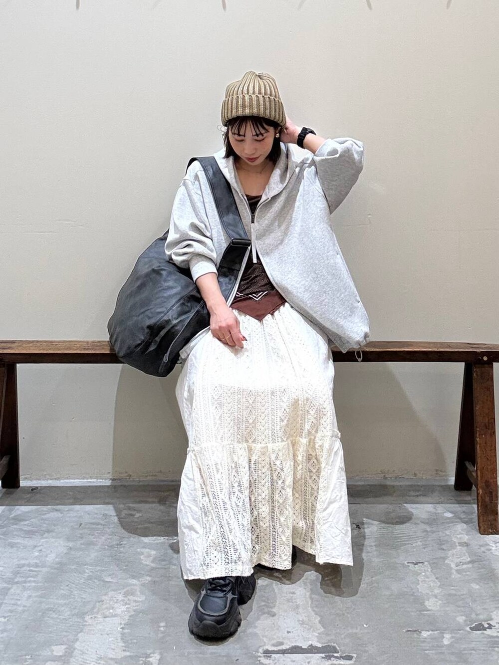 ベージュ系のスカート、ブラック系のショルダーバッグ、グレー系のパーカーを着用したレディースの秋コーディネートの2枚目の写真