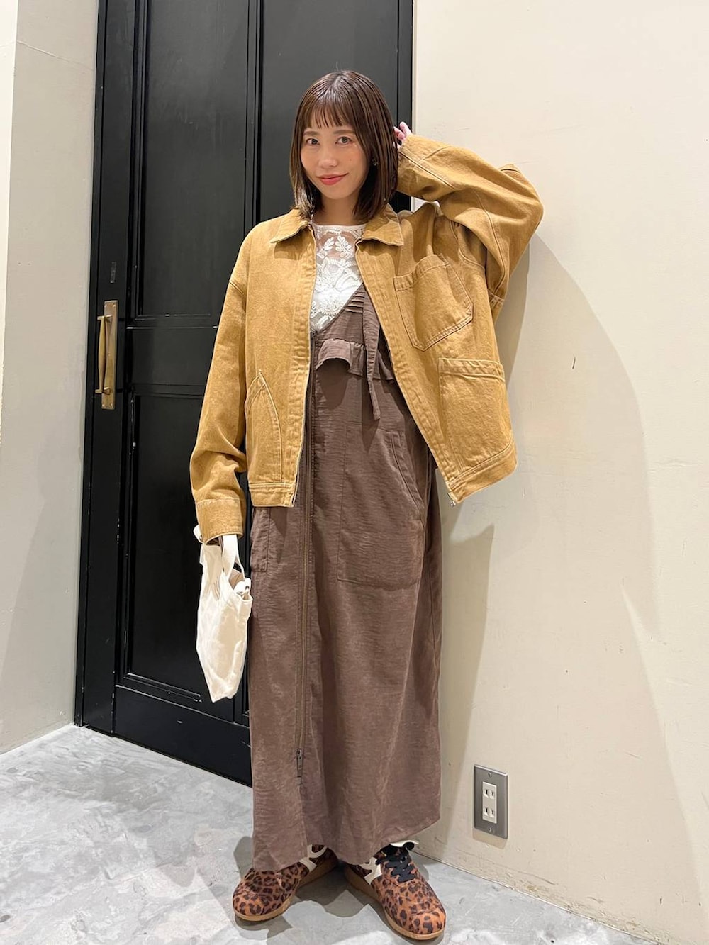 ブラウン系のジャンパースカート、ホワイト系のトートバッグ、ブラウン系のデニムジャケットを着用したレディースの春コーディネートの7枚目の写真