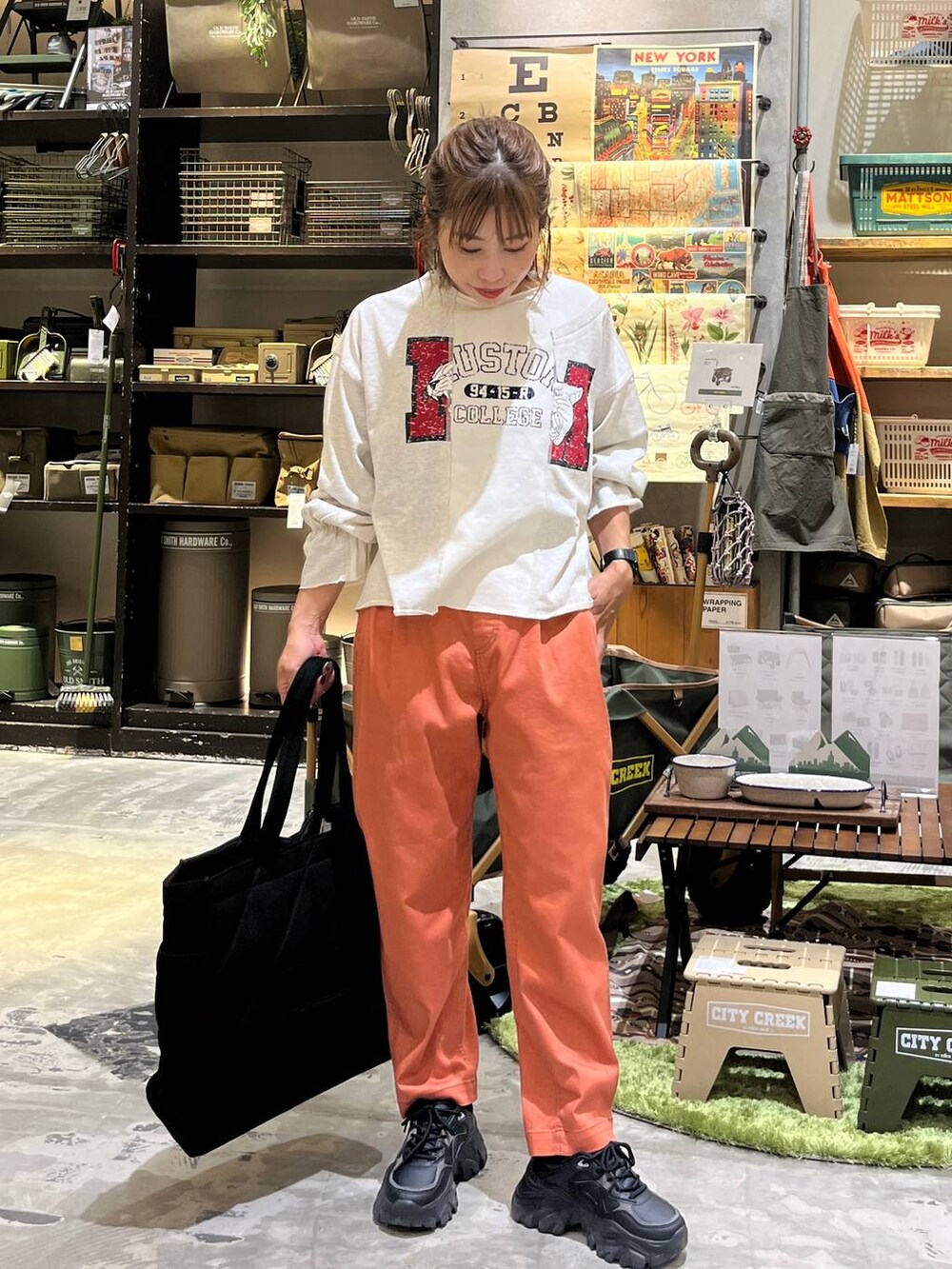 ブラック系のトートバッグ、オレンジ系のその他パンツ、ホワイト系のTシャツ/カットソーを着用したレディースの秋コーディネートの4枚目の写真