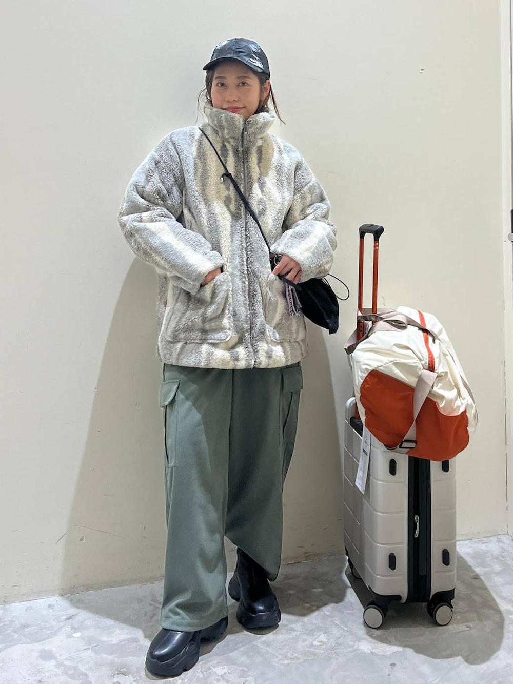 グレー系のブルゾン、ブラック系のショルダーバッグ、ブラック系のブーツを着用したレディースの冬コーディネートの4枚目の写真