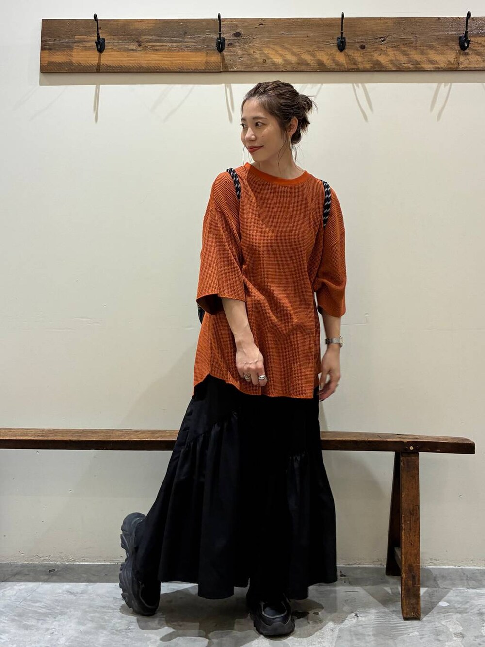 ブラック系のスカート、オレンジ系のTシャツ/カットソー、ブラック系のバックパック/リュックを着用したレディースの夏コーディネートの2枚目の写真