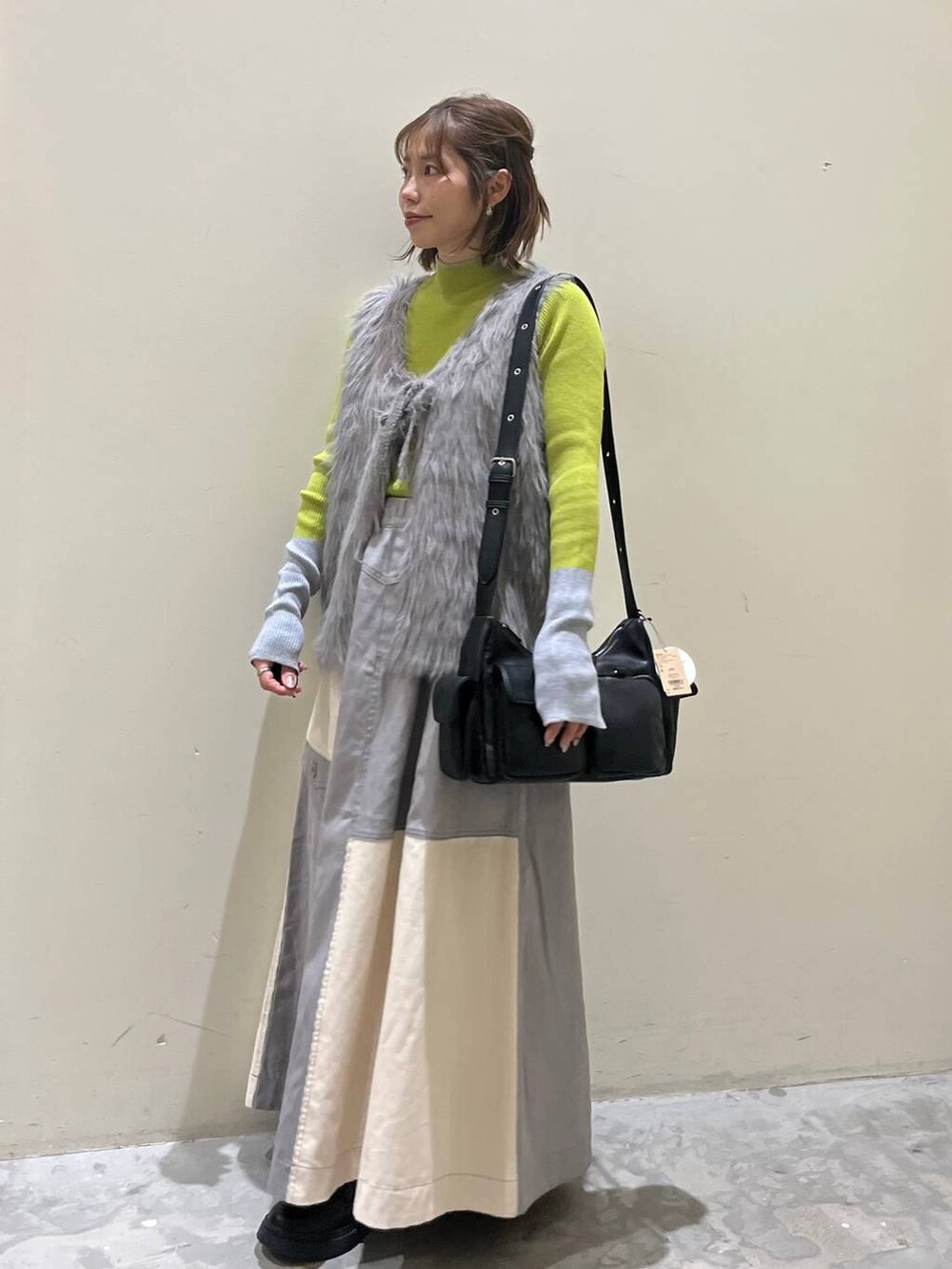 グリーン系のニット/セーター、ブラック系のブーツ、ブラック系のショルダーバッグを着用したレディースの冬コーディネートの7枚目の写真