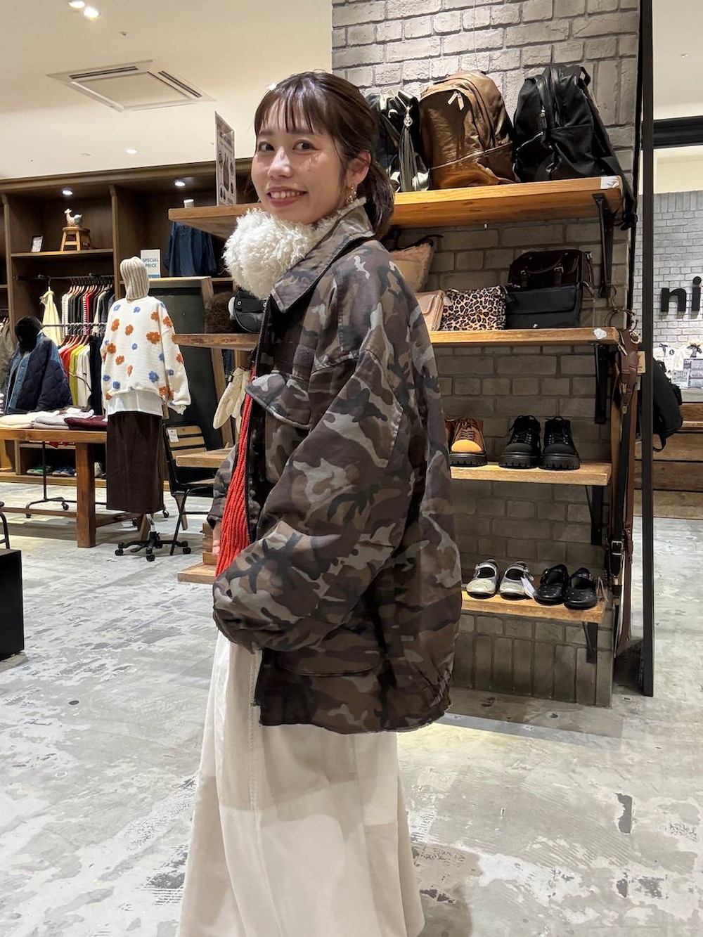 ゴールド系のスニーカー、ブラウン系のショルダーバッグ、レッド系のニット/セーターを着用したレディースの秋コーディネートの2枚目の写真