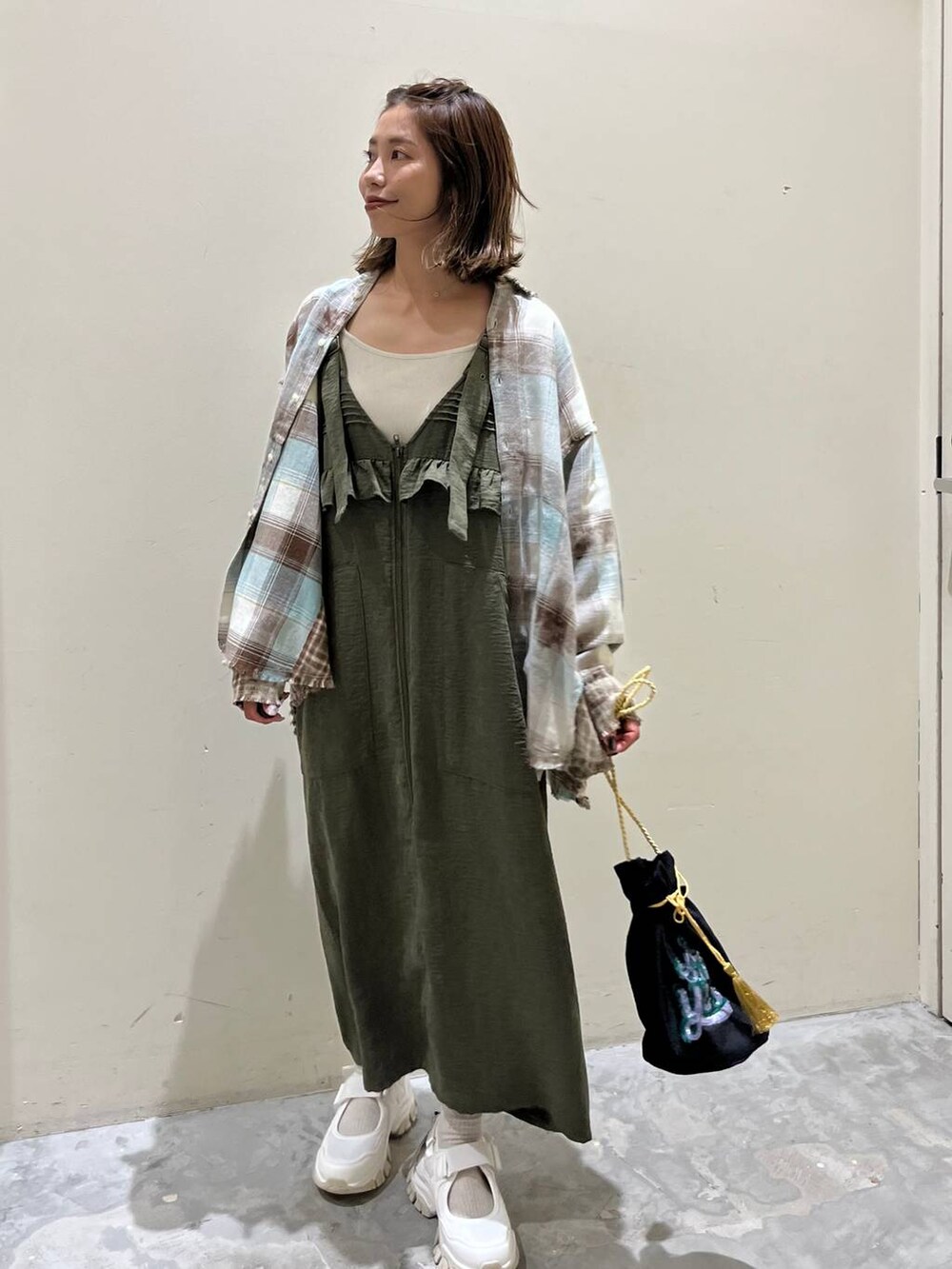 グリーン系のシャツ/ブラウス、グリーン系のジャンパースカート、ベージュ系のスニーカーを着用したレディースの秋コーディネートの5枚目の写真